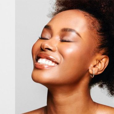 A smiling black woman with beautiful glowing skin